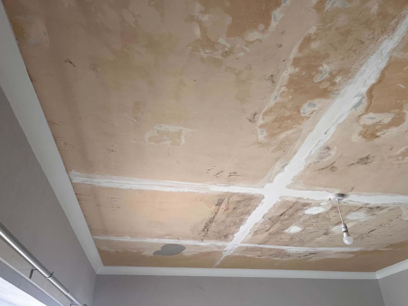 Ceiling before repair, showing water staining and patch repairs