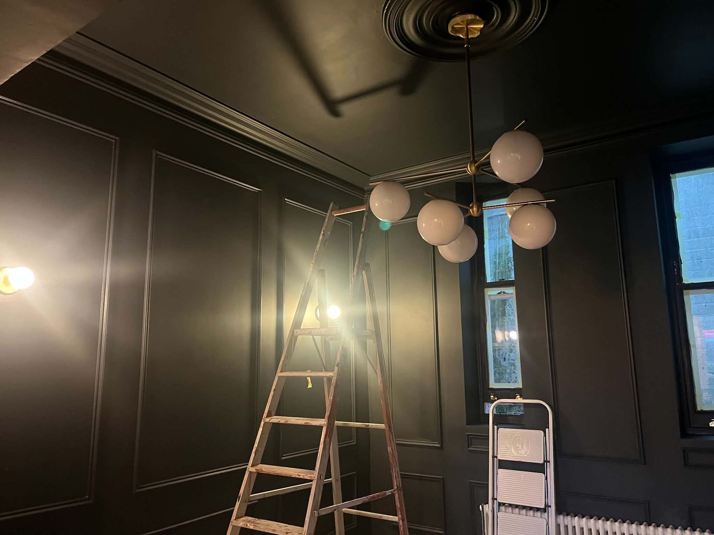 Panelled room fully repainted in deep charcoal navy, brass chandelier feature