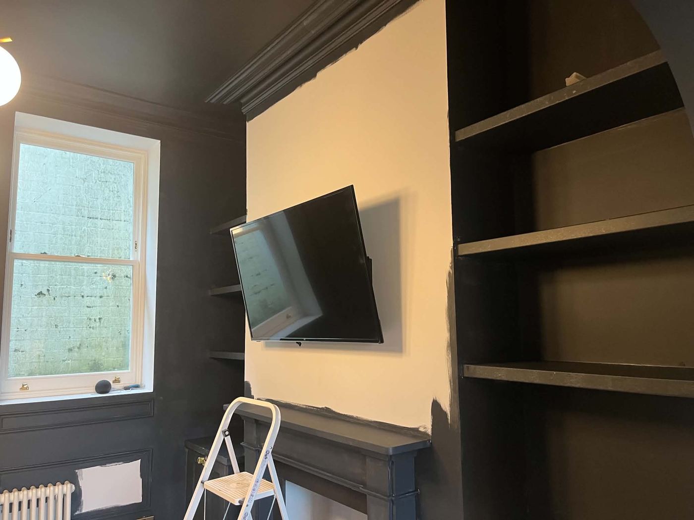 Panelled room mid-repaint, TV wall still showing original cream colour